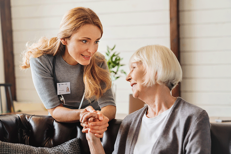 Nurse actively listening and holding hands with older adult 