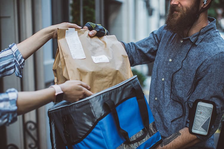 Man delivery paper bag of groceries to a home