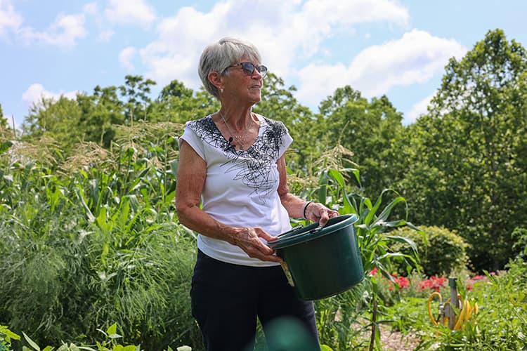 Older adult in large garden with a gardening bucket