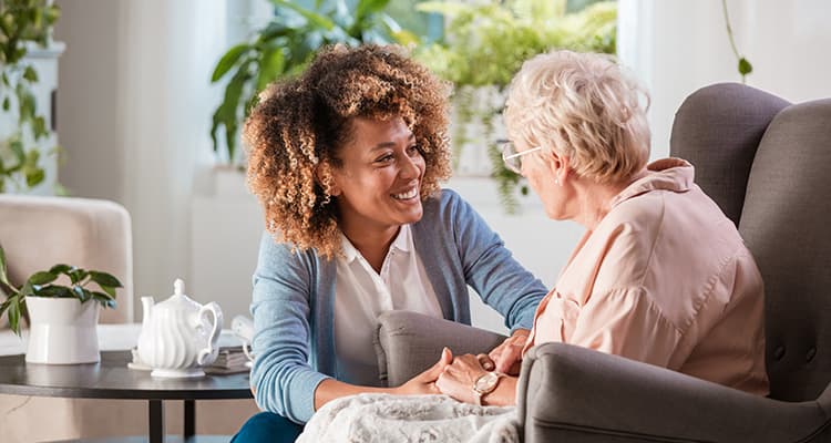 Caregiver kneeling next to chair Listening to elderly residents