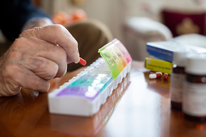 Senior hand sorting pills into medication box
