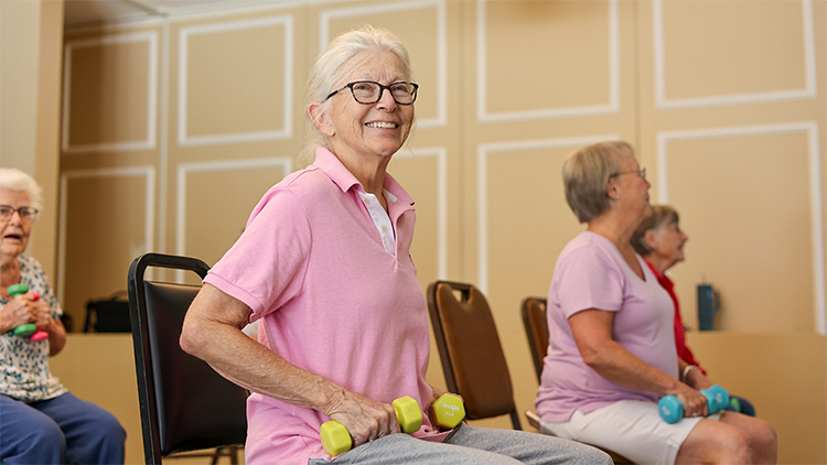 Older woman in senior fitness class with light weights