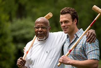 A senior man and his son playing croquet