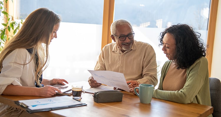 Young woman and older couple reviewing senior living documents