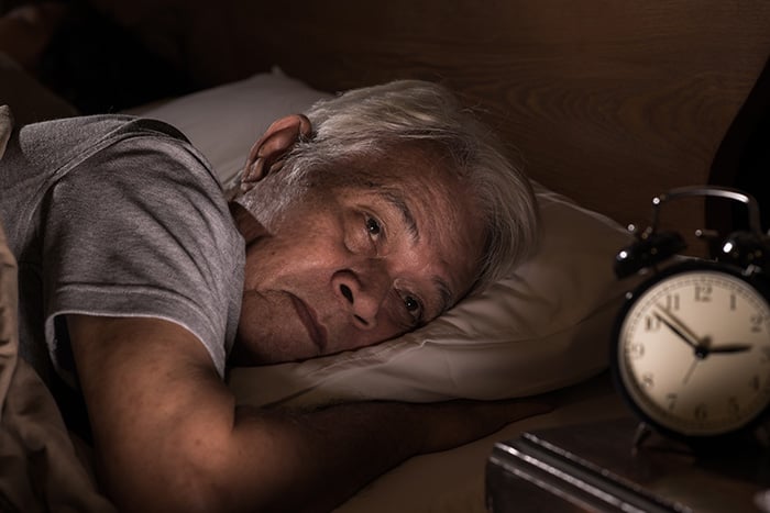 Senior man with sleep disorder wide awake with clock at 2:30am