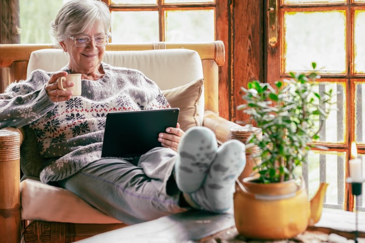 senior woman reading indoors and hydrating in the winter