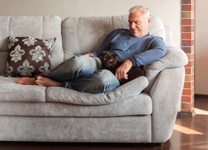senior-man-sitting-with-cat-on-couch
