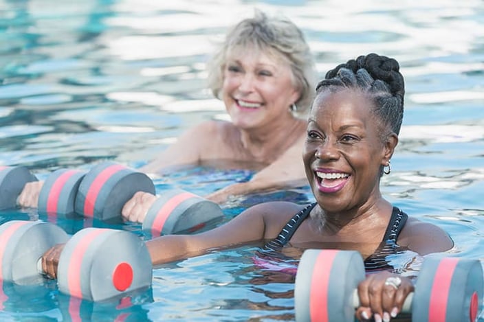 Two senior women exercising in pool