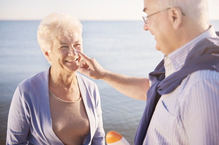 senior man putting sunscreen on senior woman