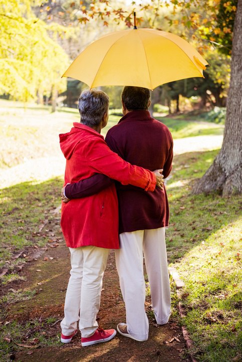 seniors standing under sun umbrella