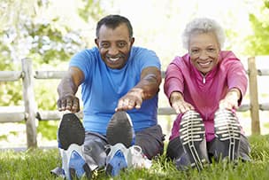 African american senior couple stretching on lawn